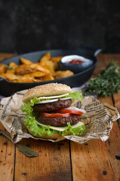 Hamburger fatto in casa con fette di patate su un tavolo di legno, rustico, fuoco selettivo