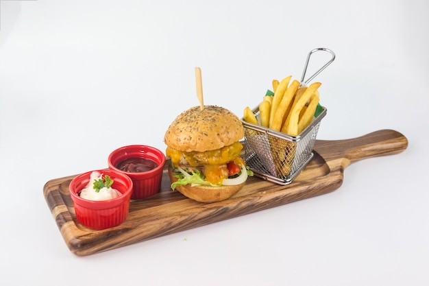 Hamburger fatto in casa con formaggio e patatine fritte nel cesto con ketchup e salsa su sfondo bianco