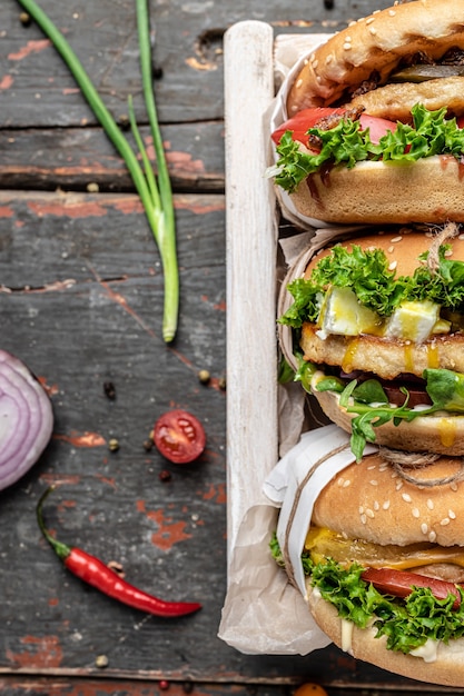 Hamburger freschi e deliziosi con verdure su fondo di legno rustico. fast food e concetto di cibo spazzatura. immagine verticale. vista dall'alto. posto per il testo