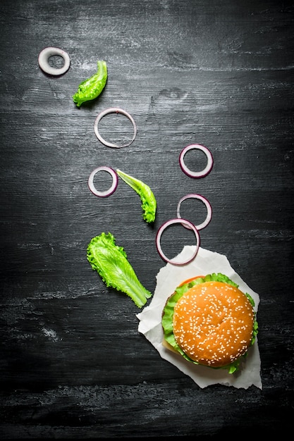 Hamburger fresco con cipolle ed erbe aromatiche. Su una lavagna nera. Vista dall'alto.