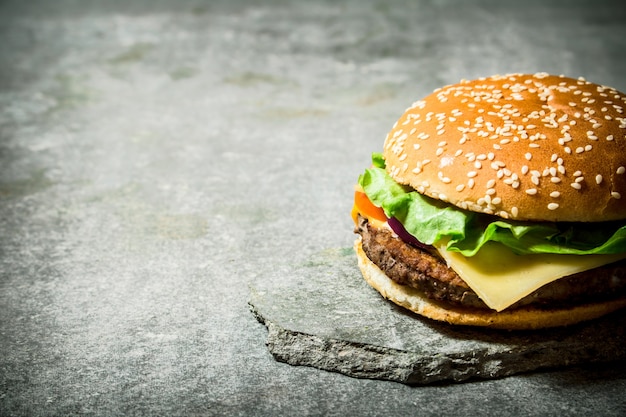 Hamburger fresco con formaggio e carne su un piedistallo di pietra. Sul tavolo di pietra.