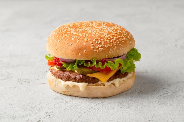Hamburger fresco e gustoso su sfondo grigio cheeseburger con manzo, pomodoro, lattuga e cipolla