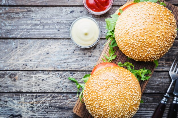 Hamburger fresco fatto in casa a tavola con salsa piccante ed erbe aromatiche su legno scuro