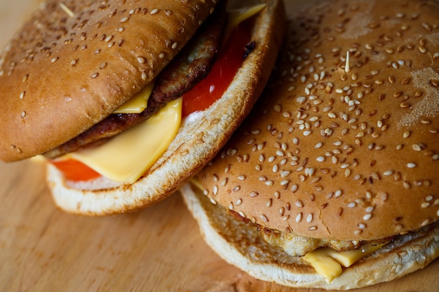 Hamburger grande e succoso con cotoletta di formaggio e pomodori. Fast food.