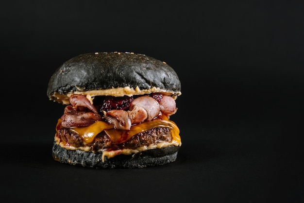 Hamburger gustoso con panino nero su sfondo nero