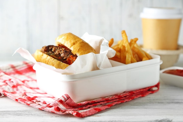 Hamburger gustoso e patatine fritte su piatto su sfondo di tavolo in legno Concetto di cibo malsano