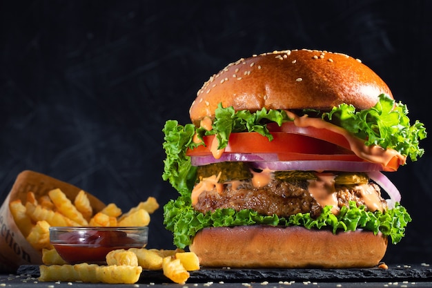 Hamburger gustoso fresco e patatine fritte sul tavolo.