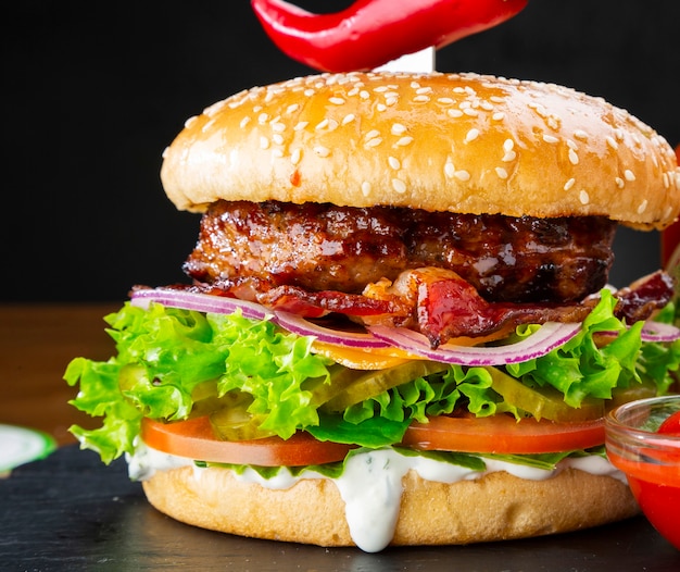 Hamburger gustoso succoso con formaggio, pancetta e pomodori. Primo piano del cheeseburger.