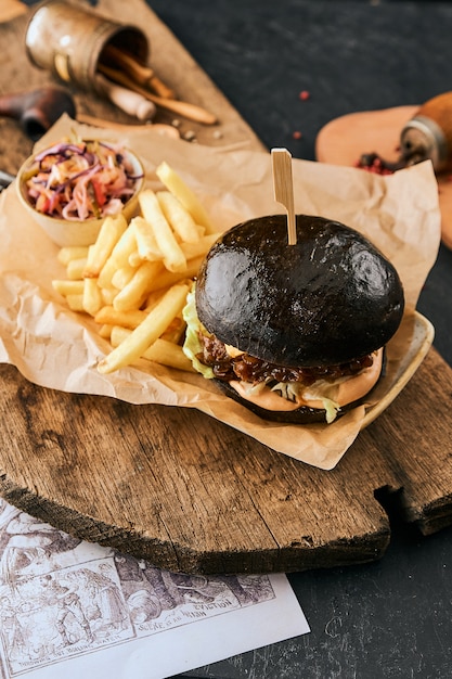 Hamburger neri deliziosi sulla carta del mestiere sul tagliere