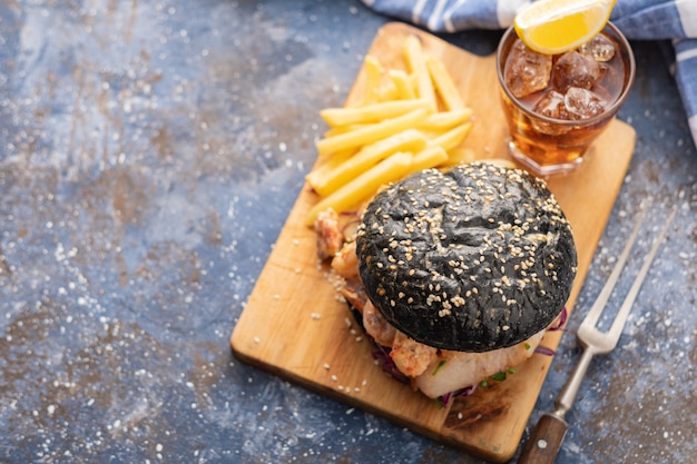 Hamburger nero con pesce e gamberetti, fishburger con gamberi, vista dall'alto.