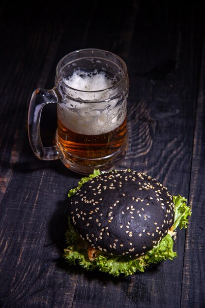 Hamburger nero e bicchiere di birra isolati sul nero. focalizzazione morbida. messa a fuoco selettiva.