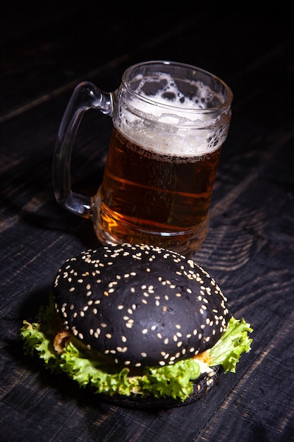 Hamburger nero e bicchiere di birra isolati sul nero. focalizzazione morbida. messa a fuoco selettiva.