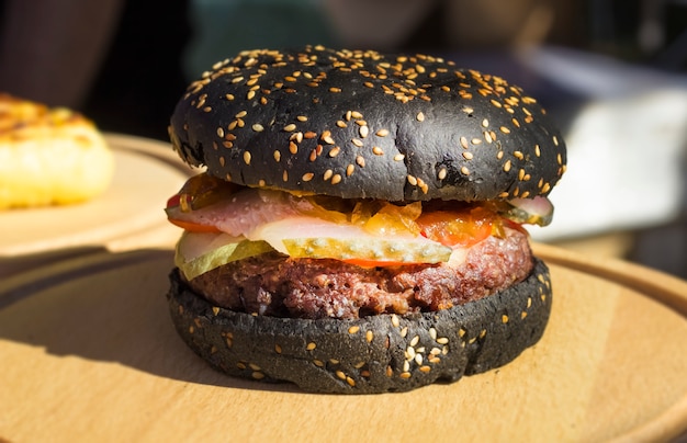 Hamburger nero su una tavola di legno.