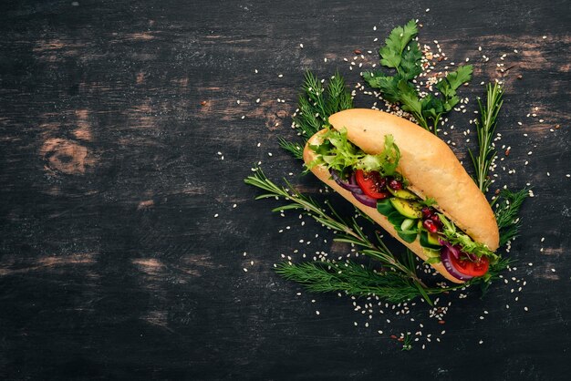 Hamburger sandwich di avocado pomodorini e foglie di lattuga su uno sfondo di legno Vista dall'alto Spazio di copia