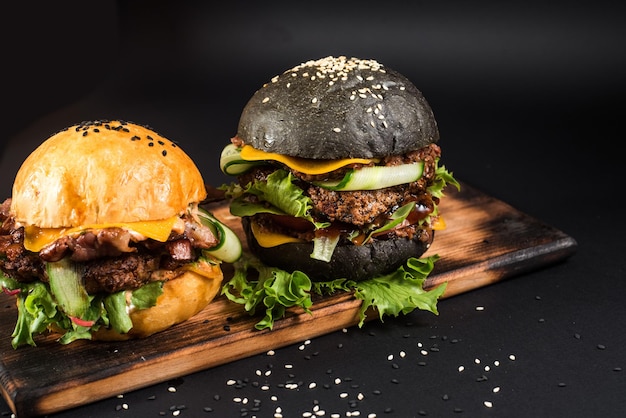 Hamburger saporiti con il panino in bianco e nero sulla scrivania di legno sui precedenti neri