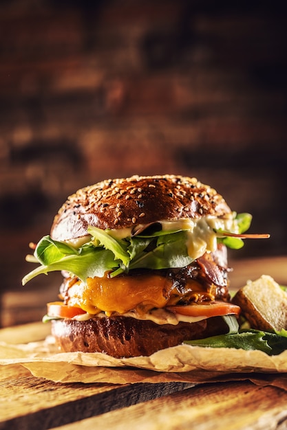 Hamburger saporito fatto in casa con lattuga ane di formaggio cipolla pancetta su scatola di legno.