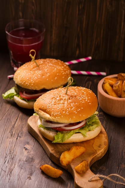 Hamburger succosi e fragranti con patatine fritte sul tavolo rustico in legno