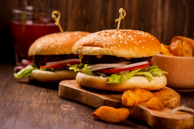 Hamburger succosi e fragranti con patatine fritte sul tavolo rustico in legno