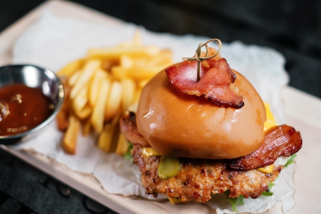 Hamburger succoso con patatine fritte e ketchup su tavola di legno