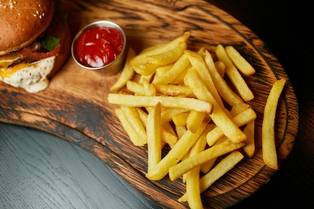 hamburger succoso su una tavola di legno con salsa e patatine fritte