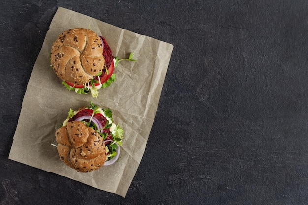 Hamburger vegano con cotoletta di barbabietola e micro verdi su sfondo nero vista dall'alto