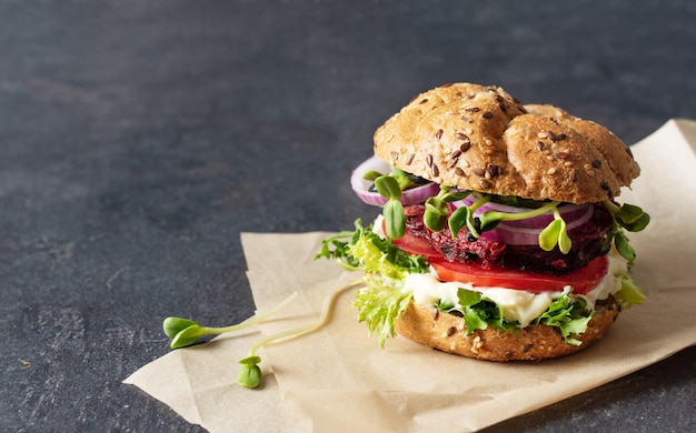 Hamburger vegano con cotoletta di barbabietola e micro verdi su sfondo nero