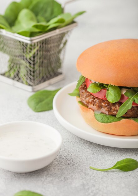 Hamburger vegetariano sano senza carne sul tagliere rotondo con verdure e spinaci sul tavolo luminoso. Vista dall'alto