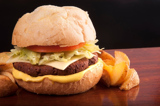 hamburger vegetariano vegano di ceci con pane di lattuga e patate rustiche sotto tavola di legno