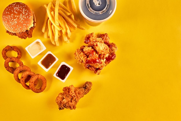 Hamburger vista dall'alto, patatine fritte e pollo fritto su sfondo giallo. Copia spazio per il tuo testo. Natura morta. Disposizione piatta