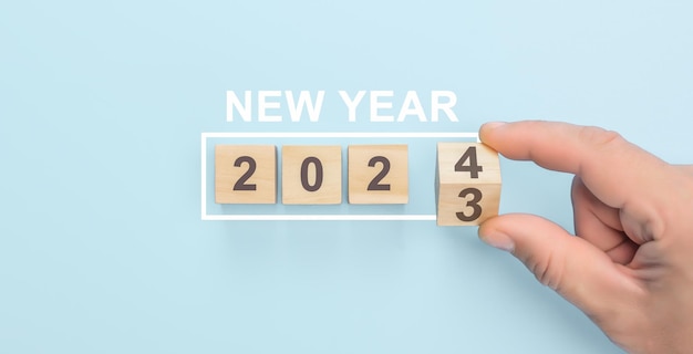 Hand flip cubo di legno cambiamento anno 2023 a 2024 Inizia il nuovo anno 2024 con obiettivo piano obiettivo concetto piano d'azione strategia nuovo anno business vision sfondo blu spazio di copia