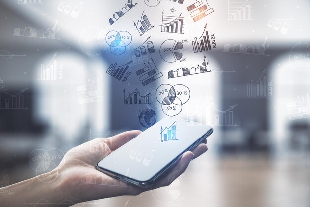 Hand holding cellphone with drawing charts and graphs