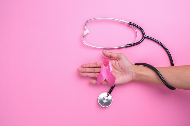 Hand holding pink ribbon breast cancer and stethoscope on pink background Breast Cancer Awareness (Ribbon rosa per il cancro al seno e stetoscopio su sfondo rosa)