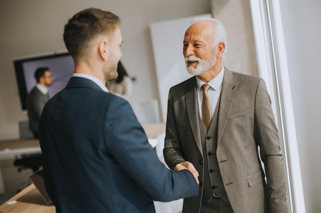 Handshake senior dell'uomo d'affari con il suo giovane collega