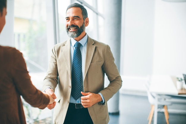 Handshake senior dell&#39;uomo d&#39;affari con la giovane donna nell&#39;ufficio