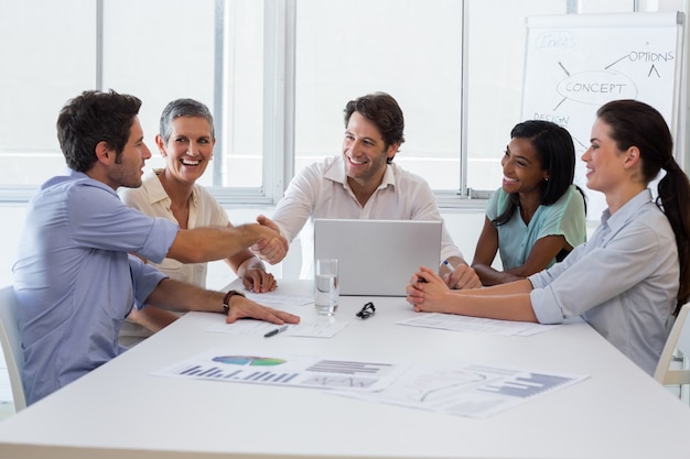 Handsome coworkers si stringono la mano in segno di approvazione