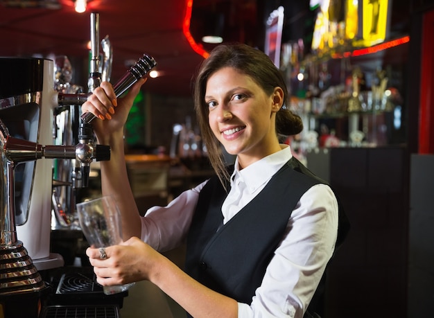 Happy barmaid tirando una pinta di birra