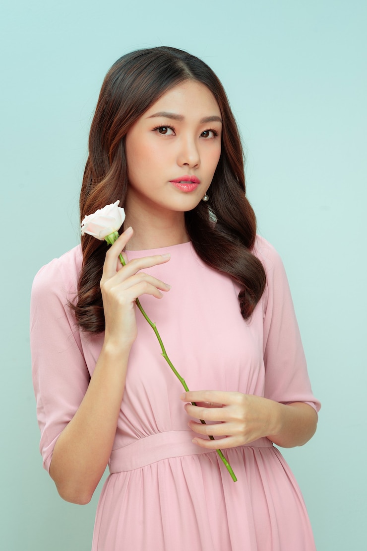 Photo happy beautiful young woman holding a pink rose