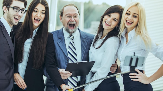 Happy business team fa un selfie con il suo capo in piedi vicino alla finestra in ufficio