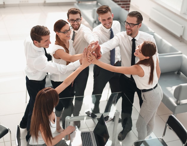 Happy business team mettendo le mani insieme il concetto di lavoro di squadra