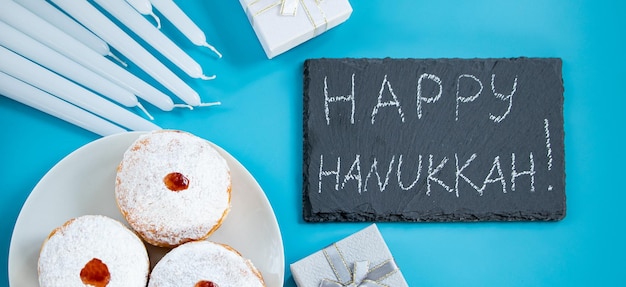 Happy Hanukkah dessert ebraico sufganiyot ciambelle su sfondo blu simbolo del giudaismo religioso vacanza iscrizione sulla lavagna