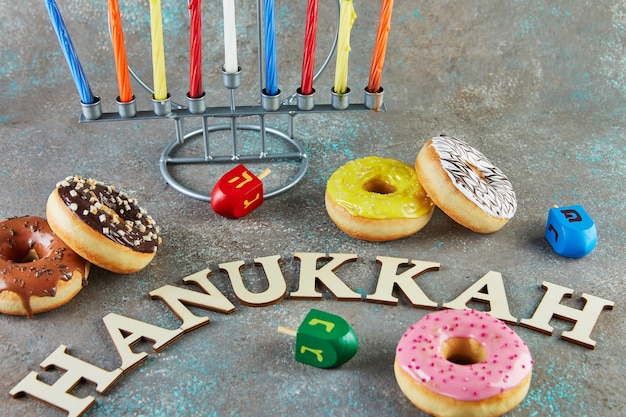 Happy Hanukkah e Hanukkah Sameach - candeliere ebraico tradizionale con candele, ciambelle e trottole con la scritta Hanukkah