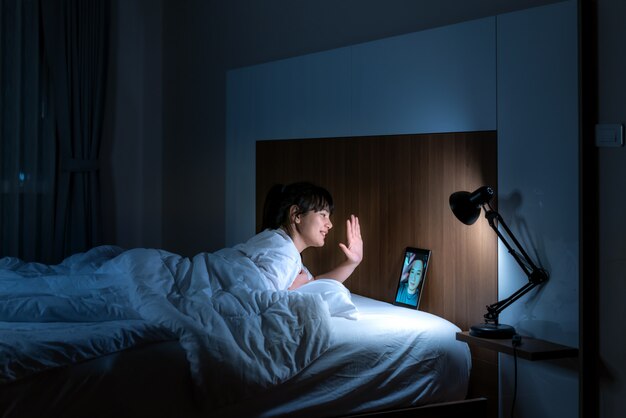 Happy hour virtuale della donna asiatica che si incontra online insieme al suo ragazzo nella videoconferenza alla buona notte prima del sonno alla notte