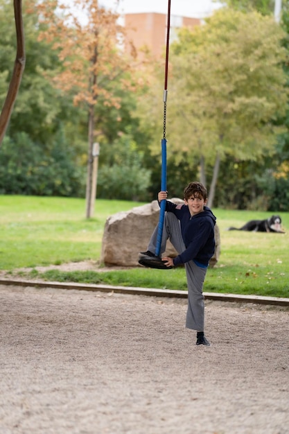 Happy Kid sorridente che sale sull'altalena del disco in un parco urbano a Madrid