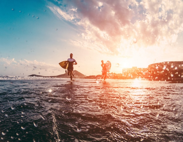 Happy urfers in esecuzione con tavole da surf sulla spiaggia