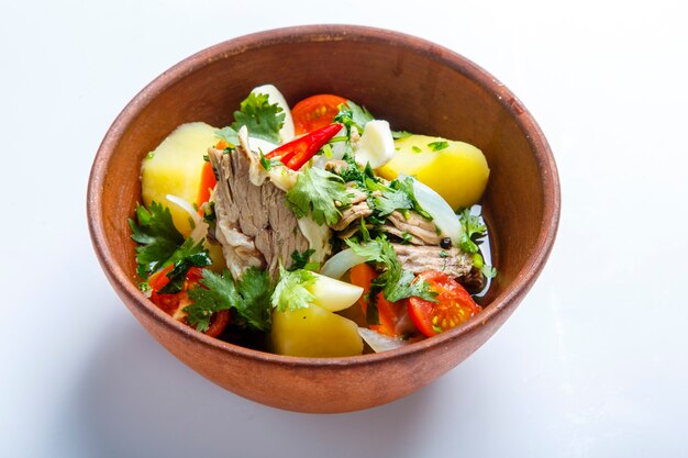 Hashlama in un piatto di argilla. Ingredienti Costine di manzo, patate, erbe aromatiche, aglio. su uno sfondo bianco