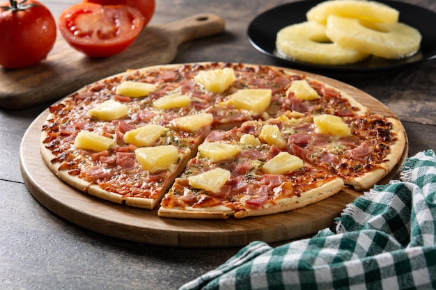 Hawaiian pizza with pineappleham and cheese on wooden table
