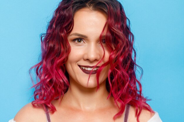 Headshot Ritratto di felice zenzero capelli rossi ragazza con lentiggini sorridente guardando la fotocamera. Sfondo blu pastello. Copia spazio.