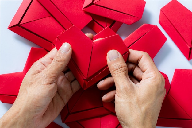 heartHands di carta che tengono piegato il cuore di Origami White BackgroundLittle ragazzi mano che tiene il cuore rosso