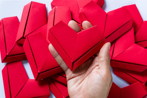 heartHands di carta che tengono piegato il cuore di Origami White BackgroundLittle ragazzi mano che tiene il cuore rosso