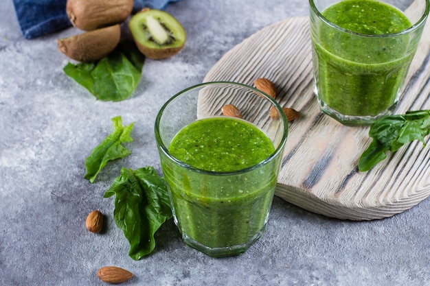 Helathy Green Smoothie con mela verde, spinaci, kiwi e mandorle noci su sfondo grigio cemento.